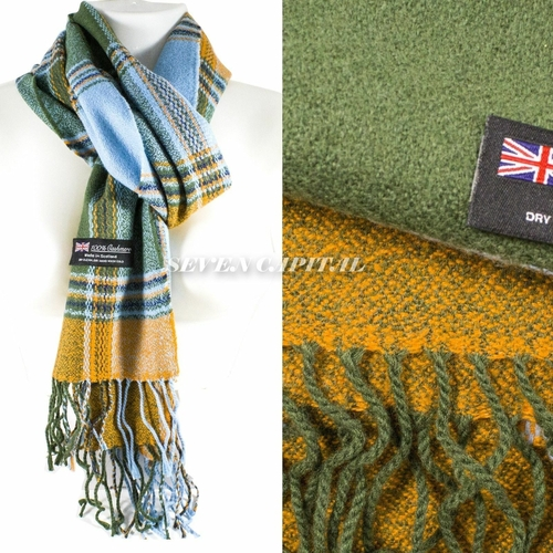 A split-view product photo of a woven scarf. The left side shows the scarf draped on a white mannequin torso against a white background, with fringe ends visible and a small black brand tag reading 'SEVEN CAPITAL' with a Union Jack.