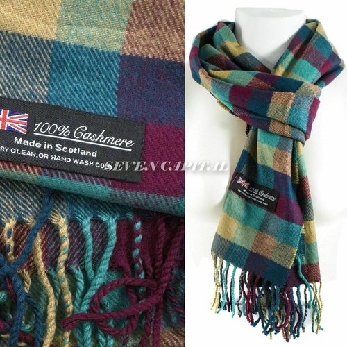 A multicolor plaid cashmere scarf with fringe, shown folded with a brand label on the left and draped on a white mannequin torso on the right. The label reads '100% Cashmere Made in Scotland' and shows a Union Jack.
