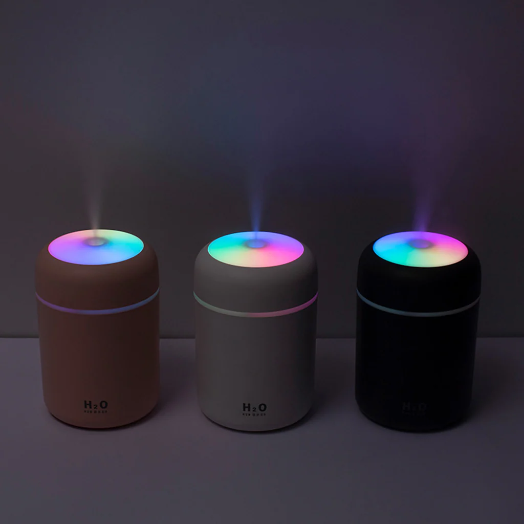 Three cylindrical humidifiers with colorful LED lights on a dark background