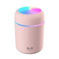 A pink cylindrical humidifier with a glowing multicolor LED light on top and a thin blue and purple light band around the middle, on a white background.