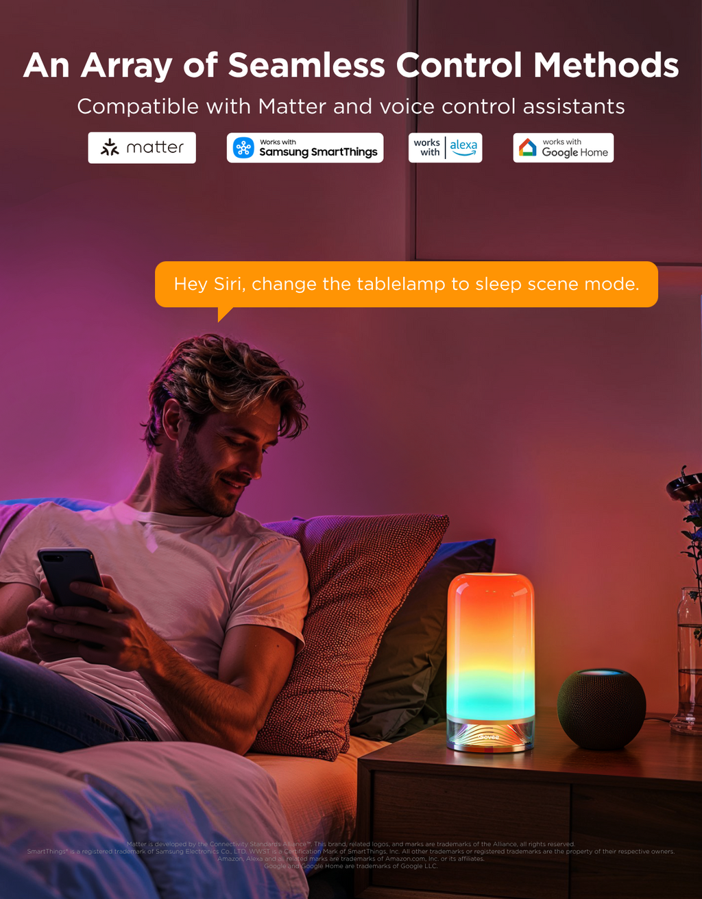 A man reclining on a bed in a bedroom, looking at a phone while a colorful LED table lamp glows on the bedside table. Text at the top reads 'An Array of Seamless Control Methods' with Matter, Samsung SmartThings, Alexa, Google Home, and Siri compatibility logos, plus an orange speech bubble saying 'Hey Siri, change the tablelamp to sleep scene mode.