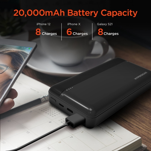 Black power bank with 20,000mAh capacity on a desk with a phone and coffee cup.
