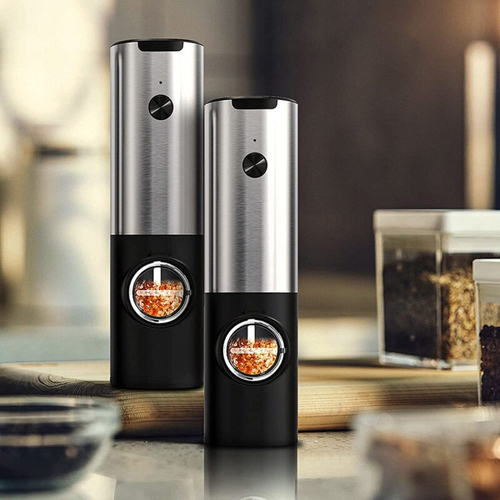 Two black and silver pepper grinders on a kitchen counter.