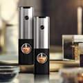 Two black and silver pepper grinders on a kitchen counter.
