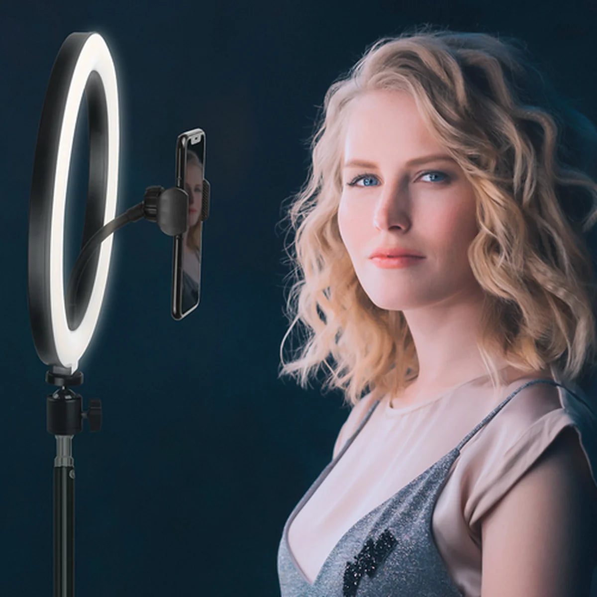 Woman posing with a ring light and smartphone on a dark background