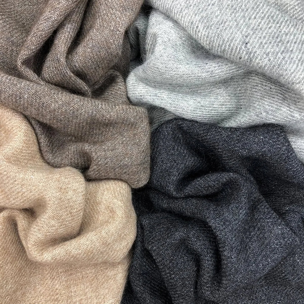 Close-up of scarves in espresso, grey, beige, and navy colors.