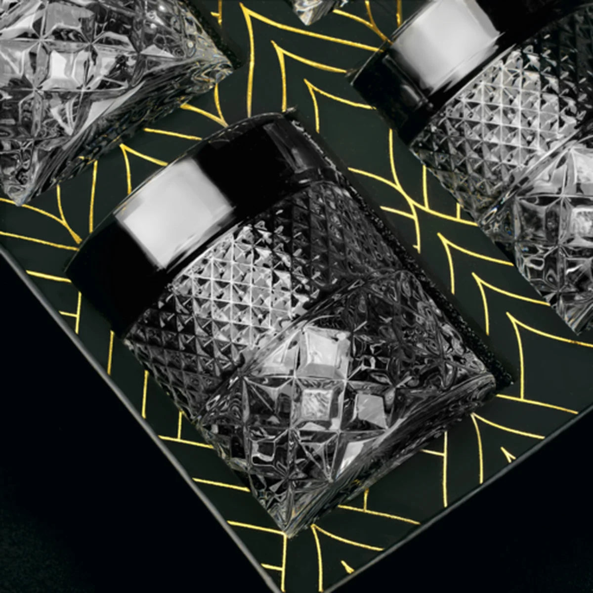 Crystal glasses with diamond cut design in a dark box with gold patterns.