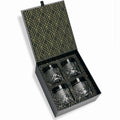Set of four glass tumblers in a black and gold patterned box.