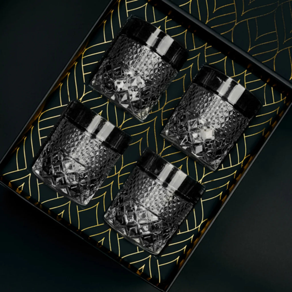 Four crystal glasses in a decorative black box with gold leaf patterns.