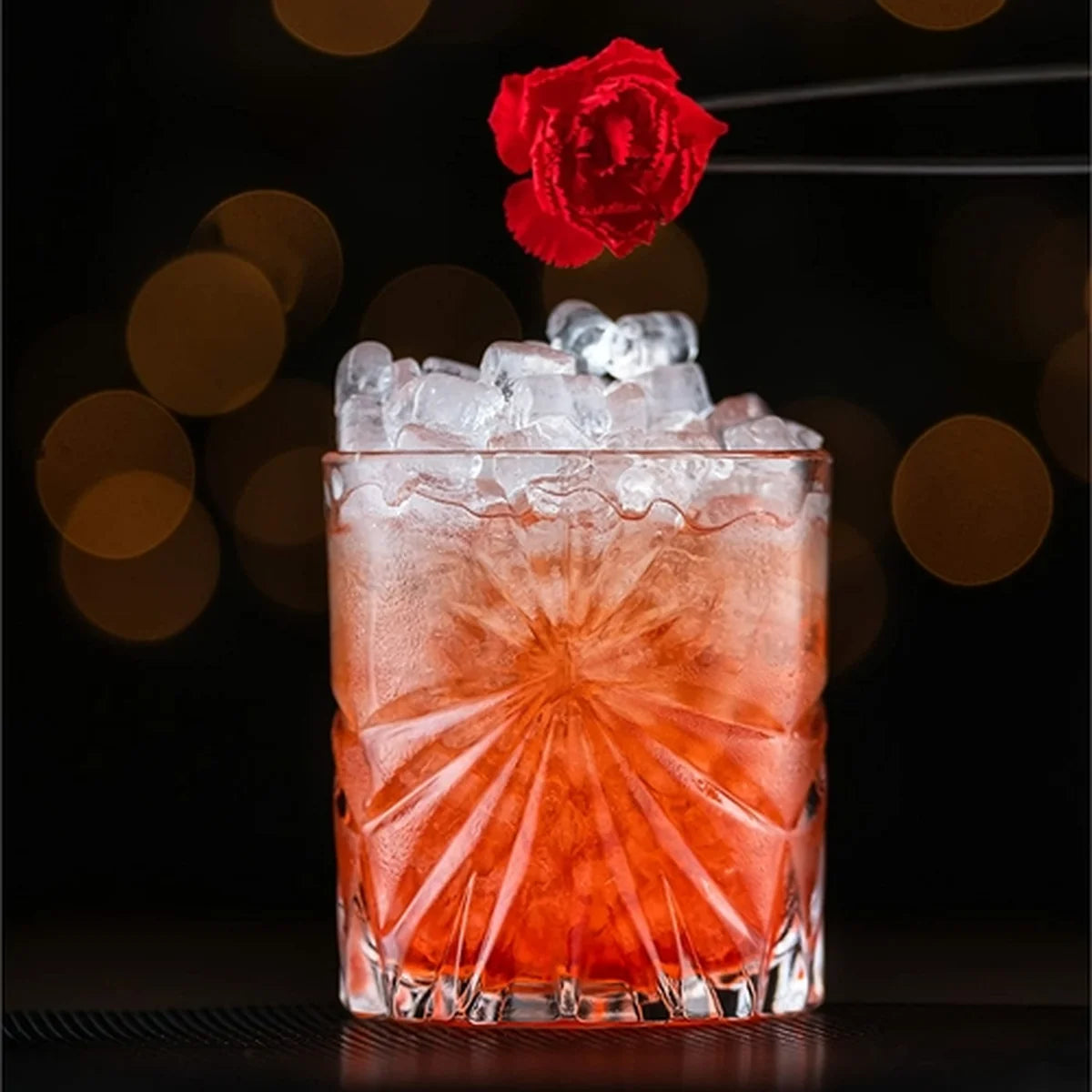 Red cocktail with ice and a red rose in a crystal glass tumbler