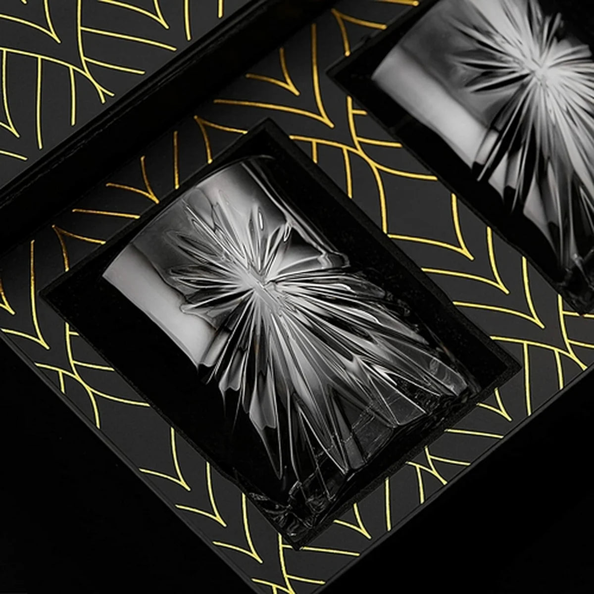 Decorative glass tumblers in a black box on a patterned surface