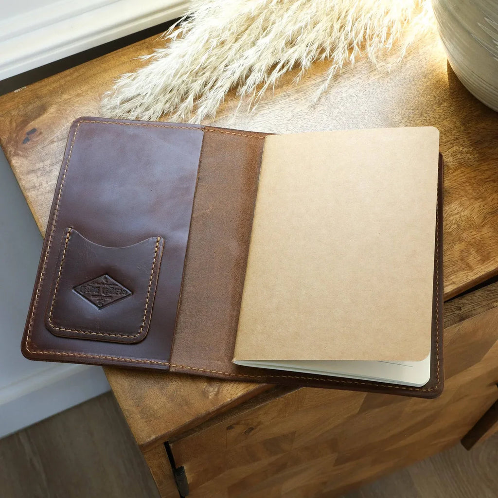 Brown leather notebook on a wooden surface with a soft white background