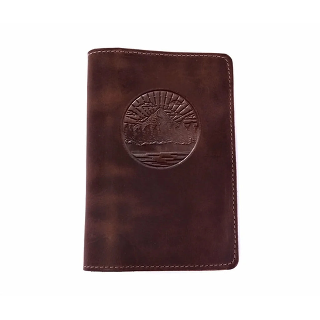 A dark brown leather passport cover featuring an embossed circular mountain and sun design on the front, set against a plain white background.