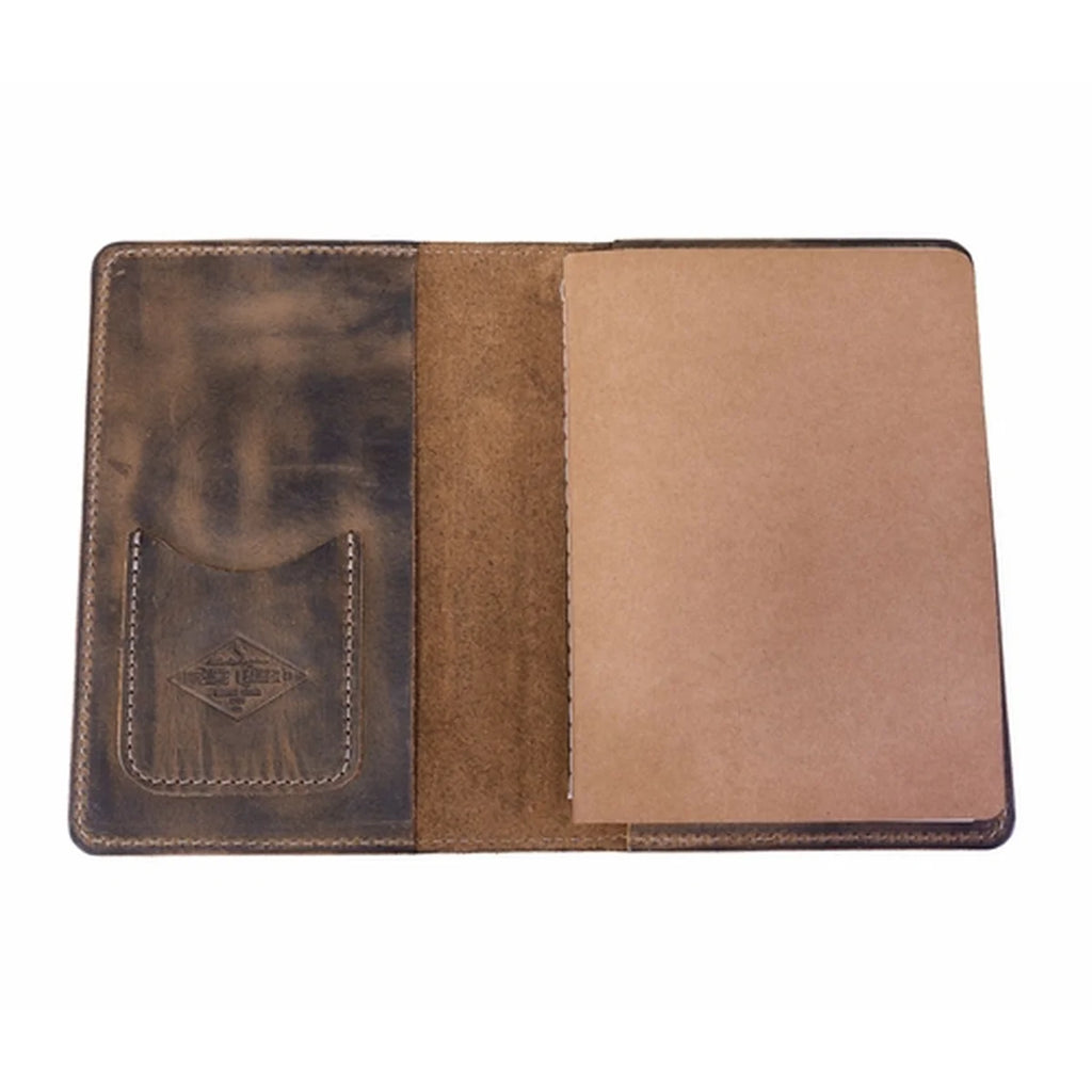 An open brown leather notebook cover or passport holder, showing a dark brown textured pocket with an embossed logo on the left and a tan interior page on the right, isolated on a white background.