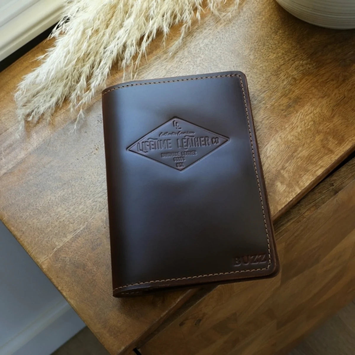 Brown leather wallet with a visible brand logo on a wooden surface.